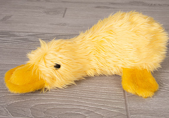 Peluche pato duckworth mullido amarillo brillante para perros descansando sobre suelos de madera
